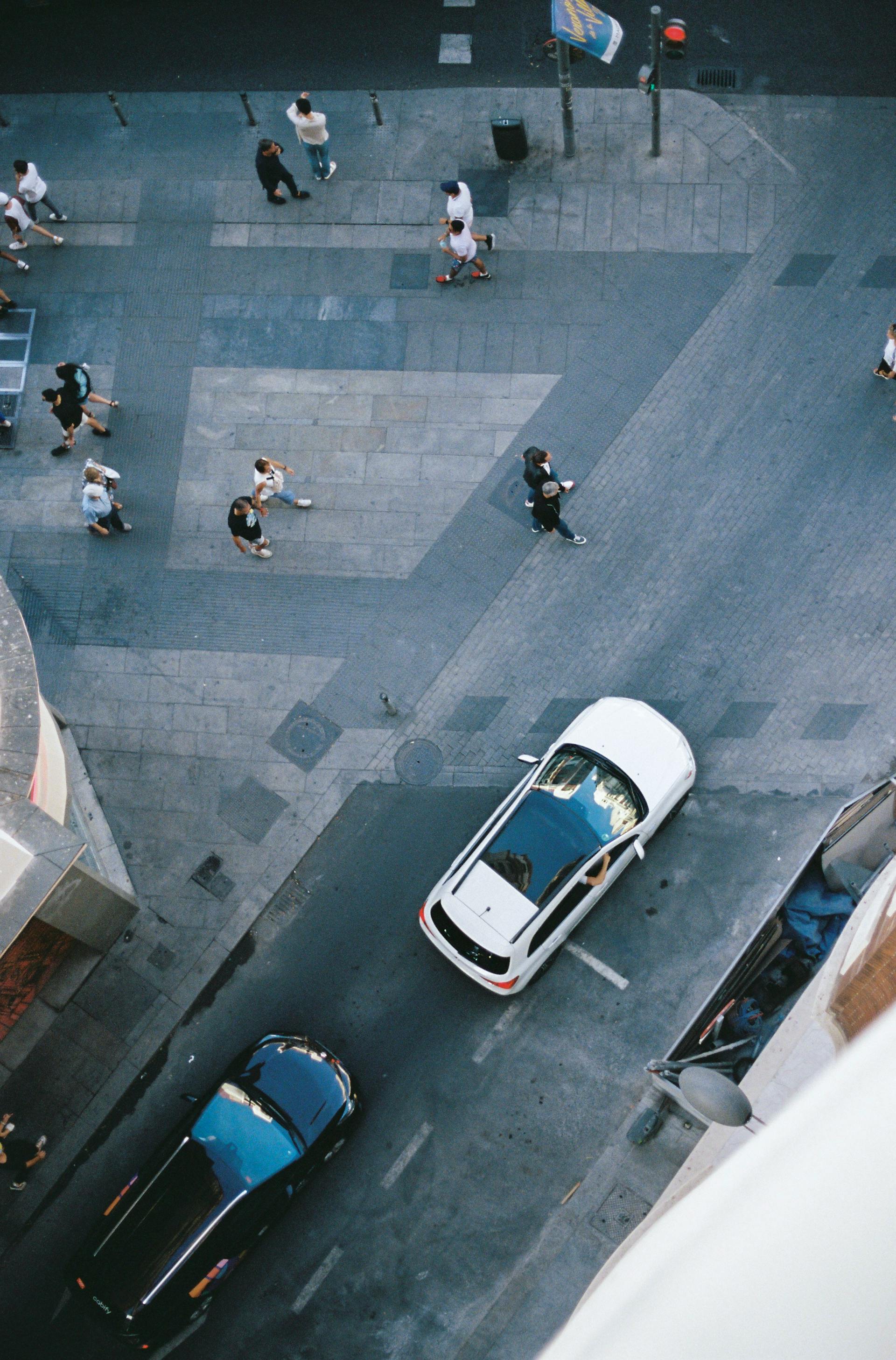 Vista aérea de personas caminando en una calle urbana con auto